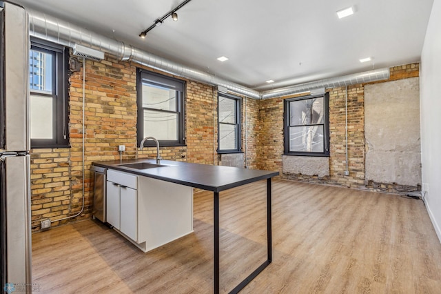 kitchen featuring sink, white cabinets, brick wall, and appliances with stainless steel finishes