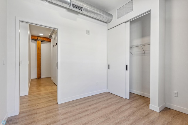 unfurnished bedroom featuring light hardwood / wood-style flooring and a closet