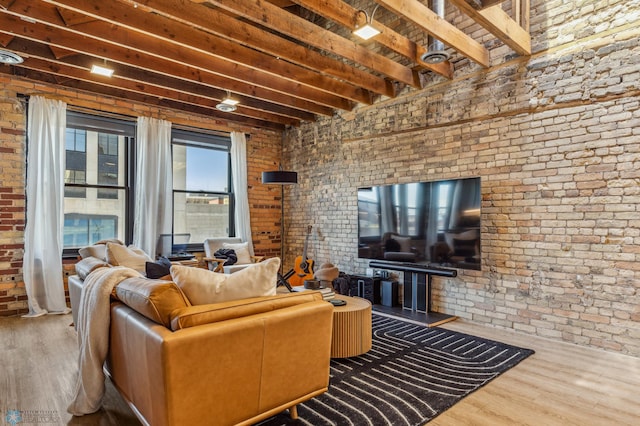 living room featuring hardwood / wood-style floors, beamed ceiling, and brick wall