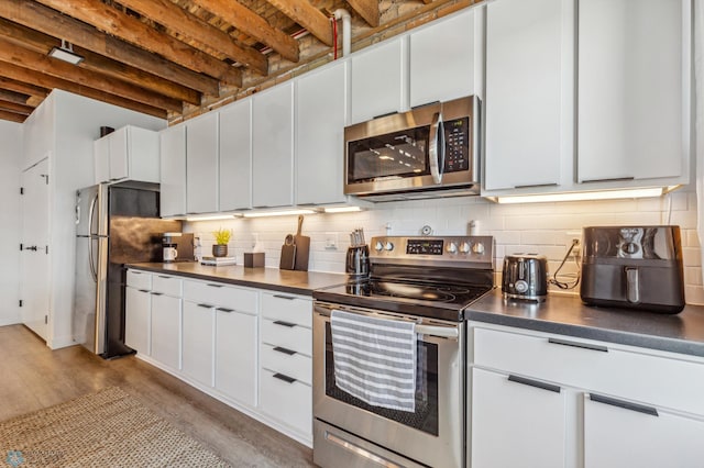 kitchen featuring appliances with stainless steel finishes, light wood-type flooring, white cabinetry, and backsplash