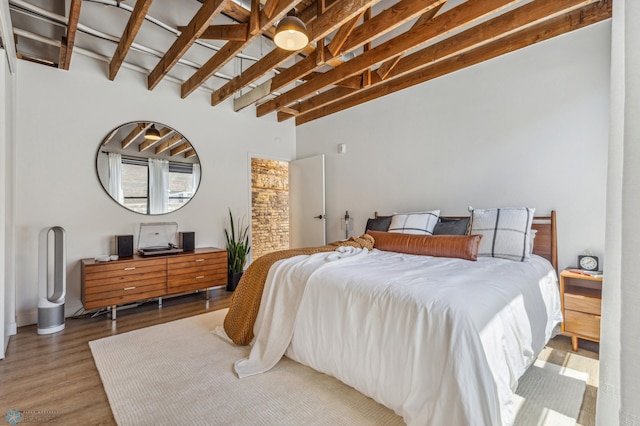 bedroom with hardwood / wood-style floors and beamed ceiling