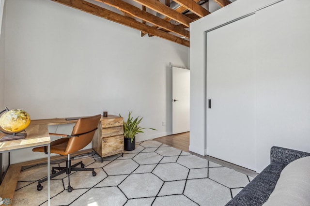 office area with beam ceiling and light hardwood / wood-style floors