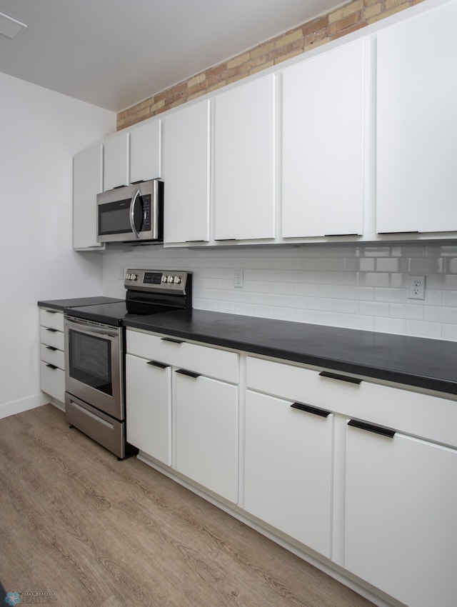 kitchen featuring white cabinets, light hardwood / wood-style floors, stainless steel appliances, and tasteful backsplash