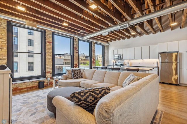 living room with light hardwood / wood-style flooring, brick wall, and sink