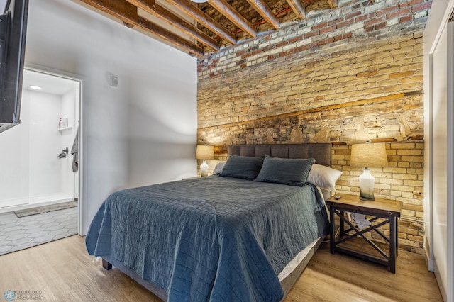 bedroom featuring beamed ceiling and light wood-type flooring