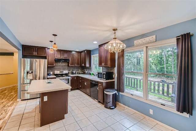 kitchen featuring hanging light fixtures, stainless steel appliances, dark brown cabinetry, a kitchen island, and decorative backsplash