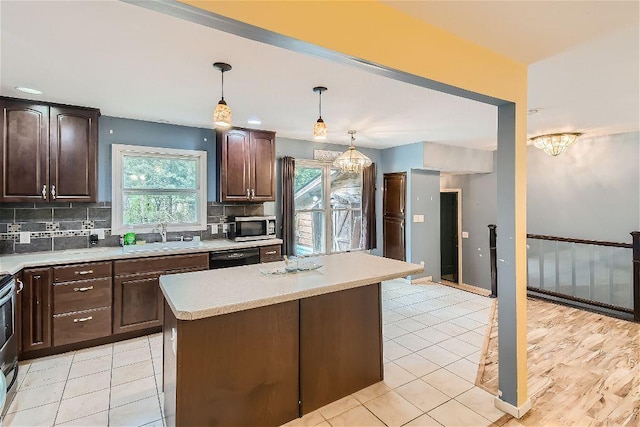 kitchen with dark brown cabinetry, sink, decorative light fixtures, a center island, and decorative backsplash