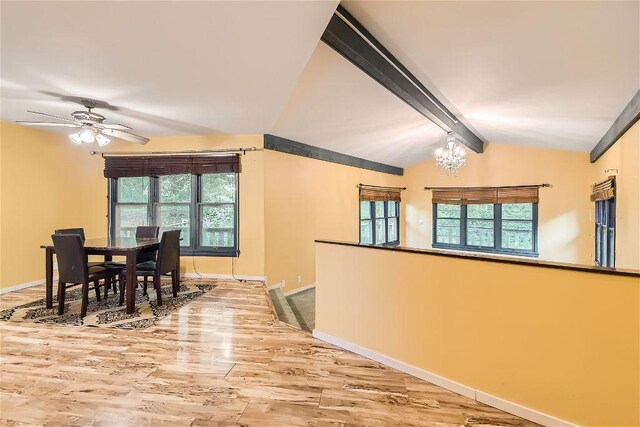 dining space with hardwood / wood-style flooring, ceiling fan with notable chandelier, lofted ceiling with beams, and a wealth of natural light