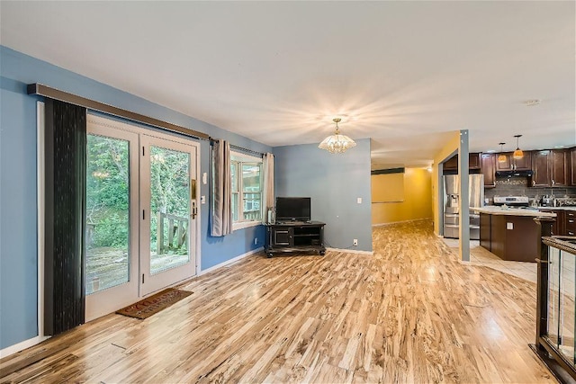 unfurnished living room with an inviting chandelier and light wood-type flooring