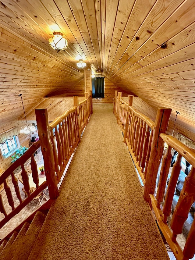 corridor featuring carpet flooring, an upstairs landing, lofted ceiling, wood walls, and wooden ceiling