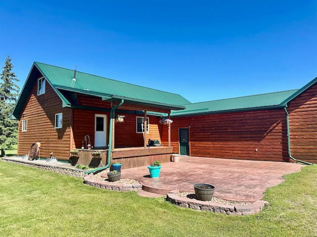 rear view of property with a lawn, metal roof, faux log siding, and a patio