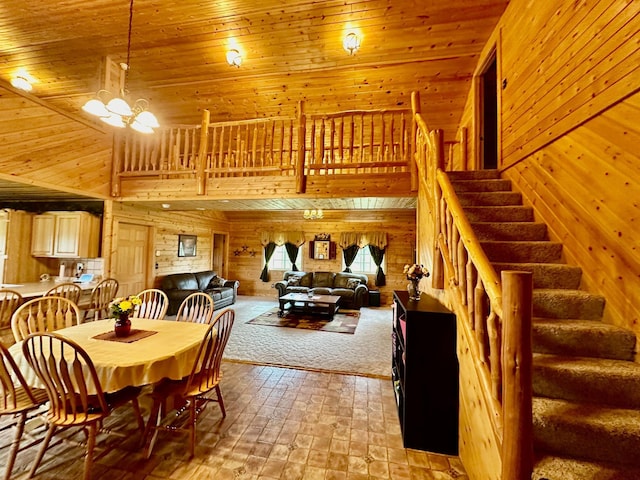 dining area featuring wood walls, a high ceiling, an inviting chandelier, wooden ceiling, and a stone fireplace