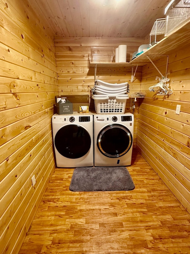 clothes washing area with washing machine and dryer, light wood-type flooring, wooden walls, and wooden ceiling