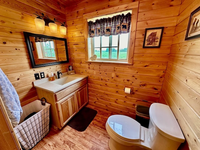 bathroom featuring wooden walls, toilet, vanity, and wood-type flooring