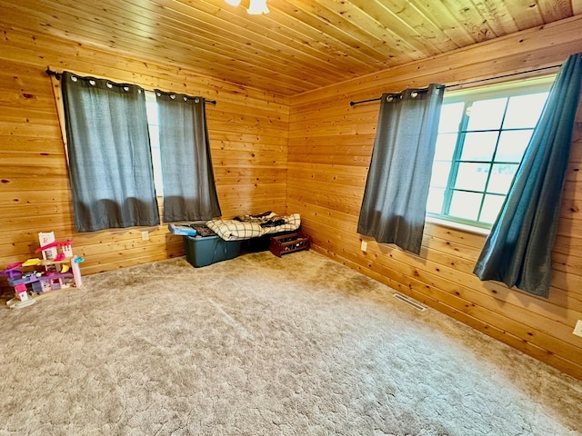 carpeted bedroom with wooden walls, wooden ceiling, and visible vents