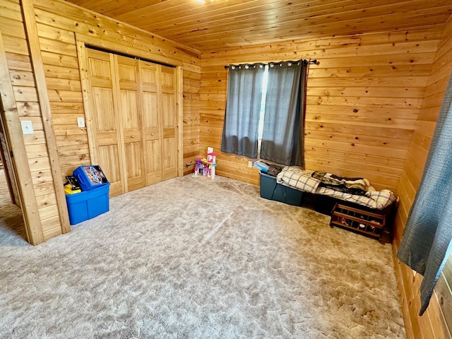 unfurnished bedroom with wood ceiling, a closet, wooden walls, and carpet