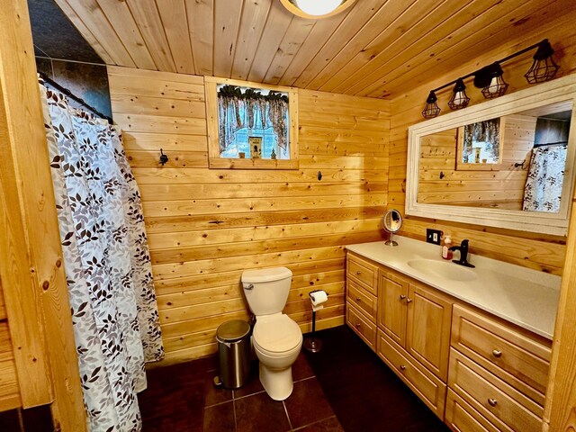 bathroom with tile patterned floors, vanity, wooden walls, wooden ceiling, and toilet