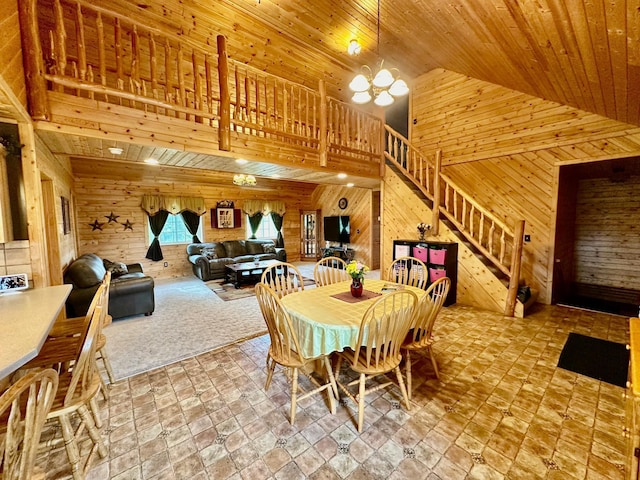 dining room featuring a chandelier, wood walls, stairs, wooden ceiling, and high vaulted ceiling