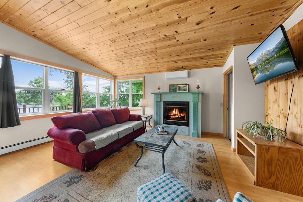 living room featuring wood ceiling, a healthy amount of sunlight, light hardwood / wood-style floors, and a wall unit AC