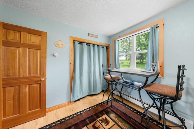 1738 White Ash Dr Unit A, Balsam Lake, WI 54810 - dining area featuring a baseboard heating unit, a textured ceiling, baseboards, and wood finished floors