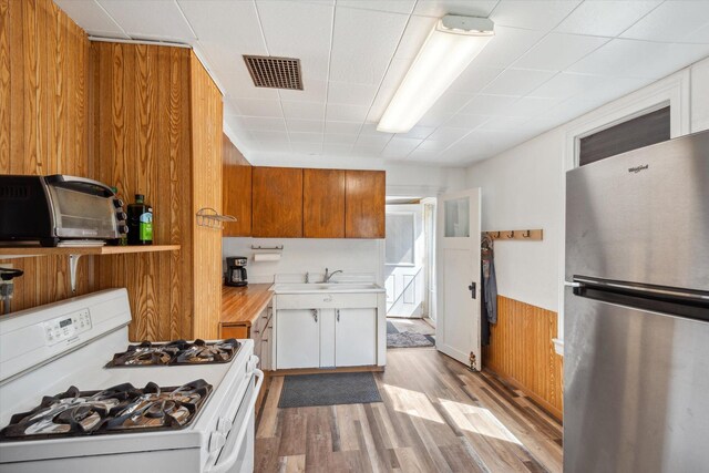 kitchen with white range with gas stovetop, visible vents, white cabinetry, light countertops, and freestanding refrigerator