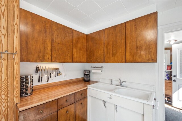 kitchen with brown cabinetry, light countertops, and a sink