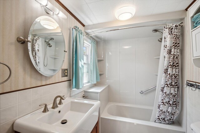 bathroom featuring tile walls, shower / bath combo with shower curtain, and a sink