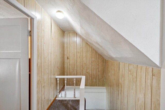 additional living space featuring lofted ceiling and wooden walls