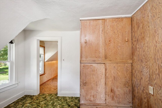 bonus room with a textured ceiling, dark carpet, and baseboards