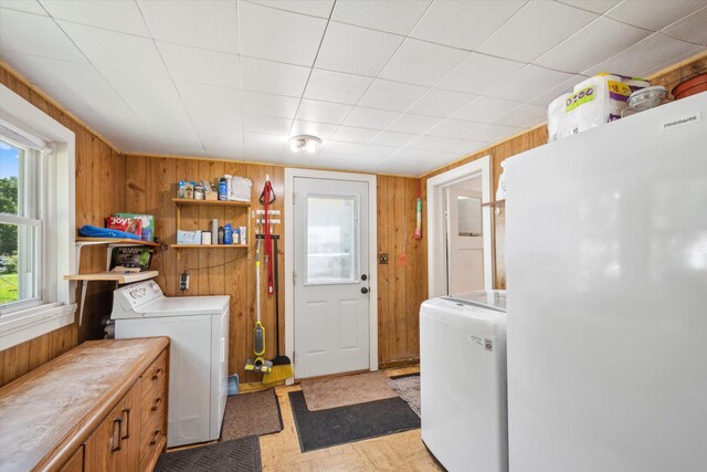 laundry area featuring laundry area, light floors, independent washer and dryer, and wooden walls