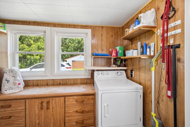 clothes washing area featuring laundry area, wooden walls, and washer / clothes dryer