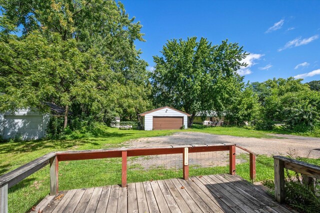 deck with a garage, a lawn, and an outdoor structure