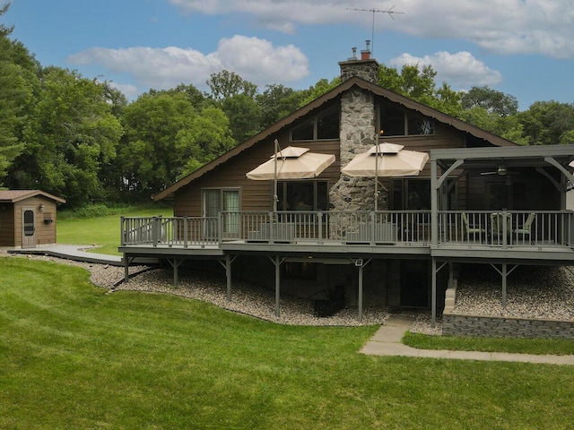 back of property with a wooden deck, a yard, and a storage unit