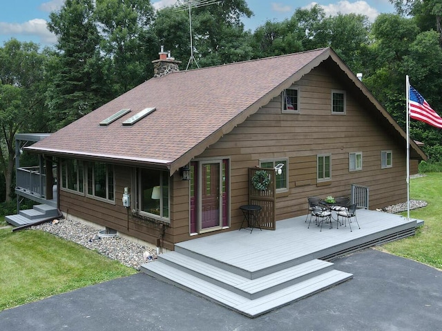 back of property with a wooden deck and a lawn