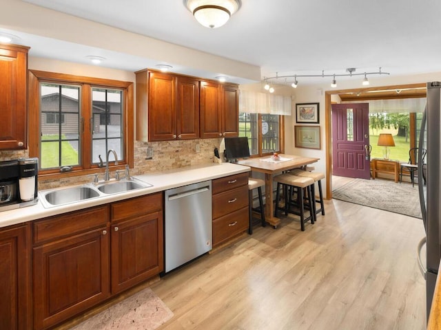 kitchen featuring sink, light wood-type flooring, plenty of natural light, appliances with stainless steel finishes, and decorative backsplash