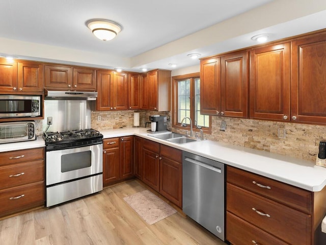 kitchen with tasteful backsplash, stainless steel appliances, sink, and light wood-type flooring