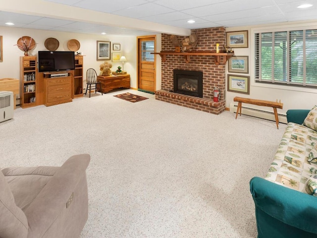 carpeted living room with a drop ceiling, a brick fireplace, and baseboard heating