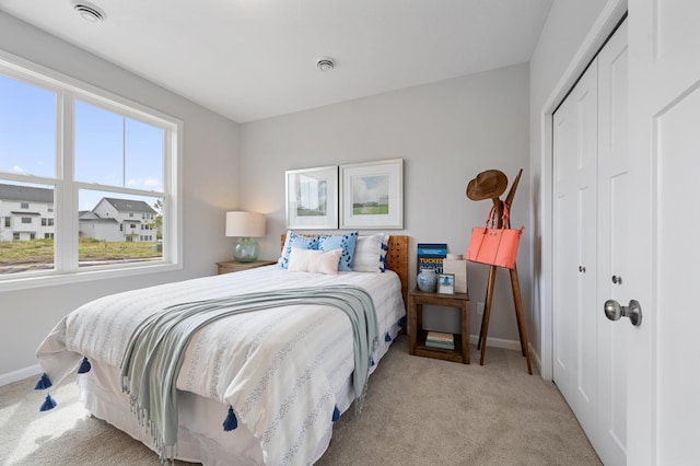 bedroom with visible vents, light colored carpet, a closet, and baseboards