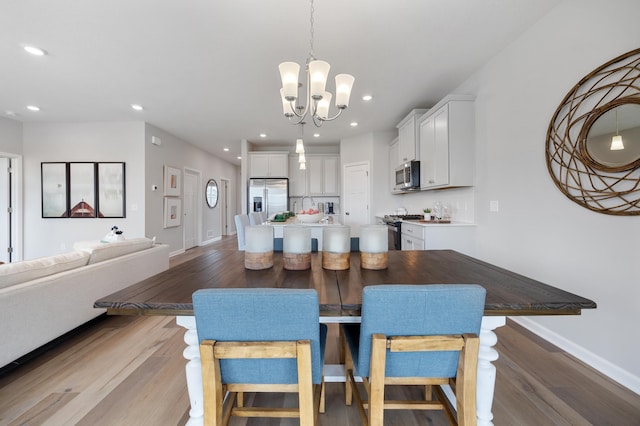 dining space featuring recessed lighting, baseboards, an inviting chandelier, and wood finished floors