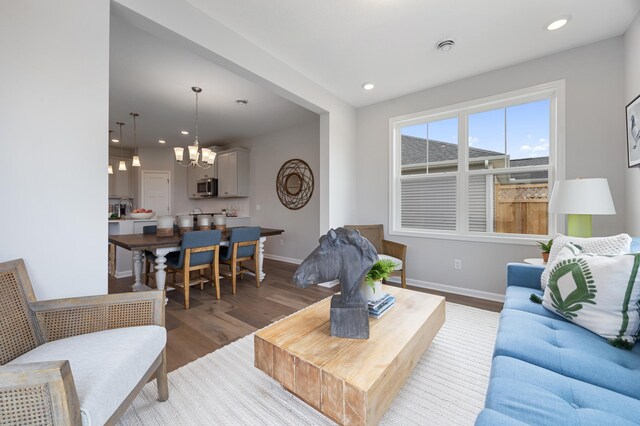 living room featuring a notable chandelier, dark hardwood / wood-style floors, and sink