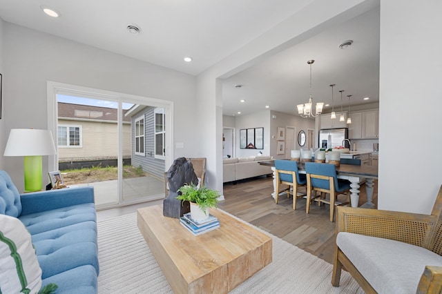 living area featuring an inviting chandelier, light wood-style flooring, recessed lighting, and visible vents