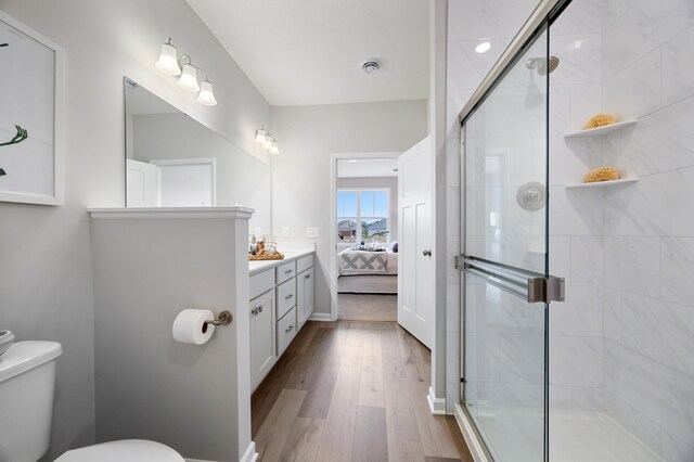 bathroom featuring hardwood / wood-style floors, a shower with shower door, vanity, and toilet