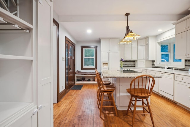 kitchen with white cabinetry, a breakfast bar area, hanging light fixtures, a center island, and white dishwasher