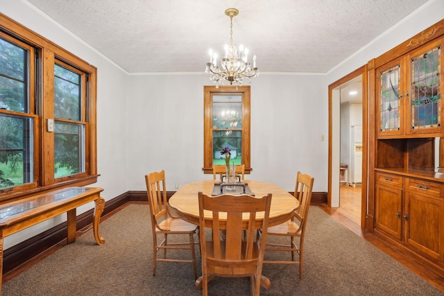 dining area with an inviting chandelier, ornamental molding, a textured ceiling, and hardwood / wood-style flooring