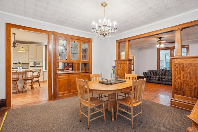 dining area featuring ornamental molding, ceiling fan with notable chandelier, and light hardwood / wood-style floors