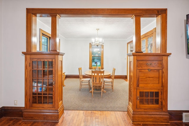 dining area with ornamental molding, light hardwood / wood-style floors, a textured ceiling, and a notable chandelier