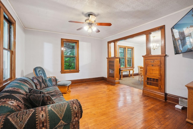 living room with ceiling fan, ornamental molding, wood-type flooring, and a textured ceiling