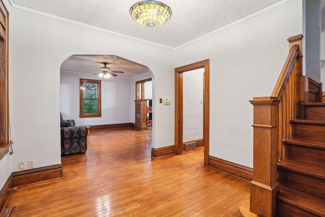 interior space with ornamental molding, a textured ceiling, and light wood-type flooring