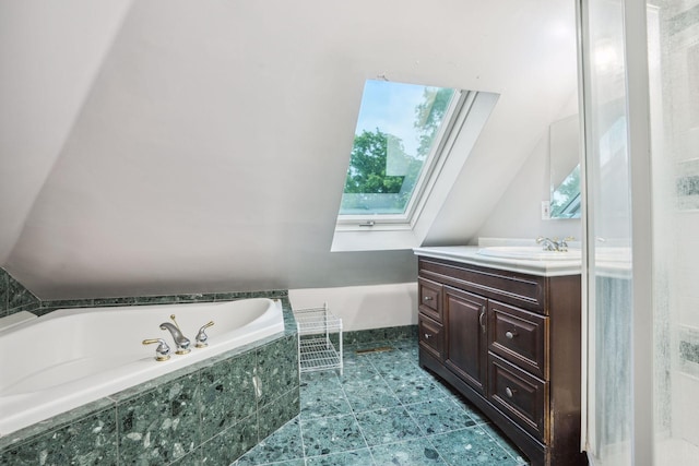 bathroom with vanity, tiled bath, and vaulted ceiling with skylight