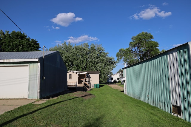 view of yard with a garage, an outdoor structure, and a wooden deck